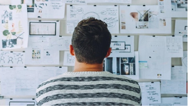 A man looking at papers on the wall