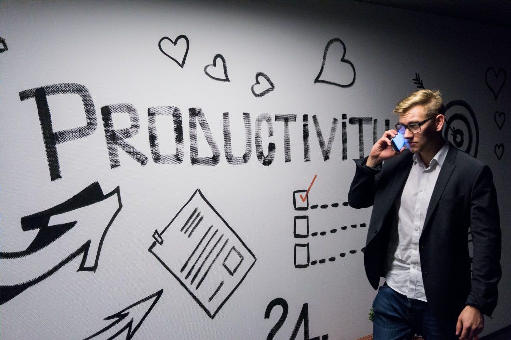 A person standing next to a wall that has productivity written on it